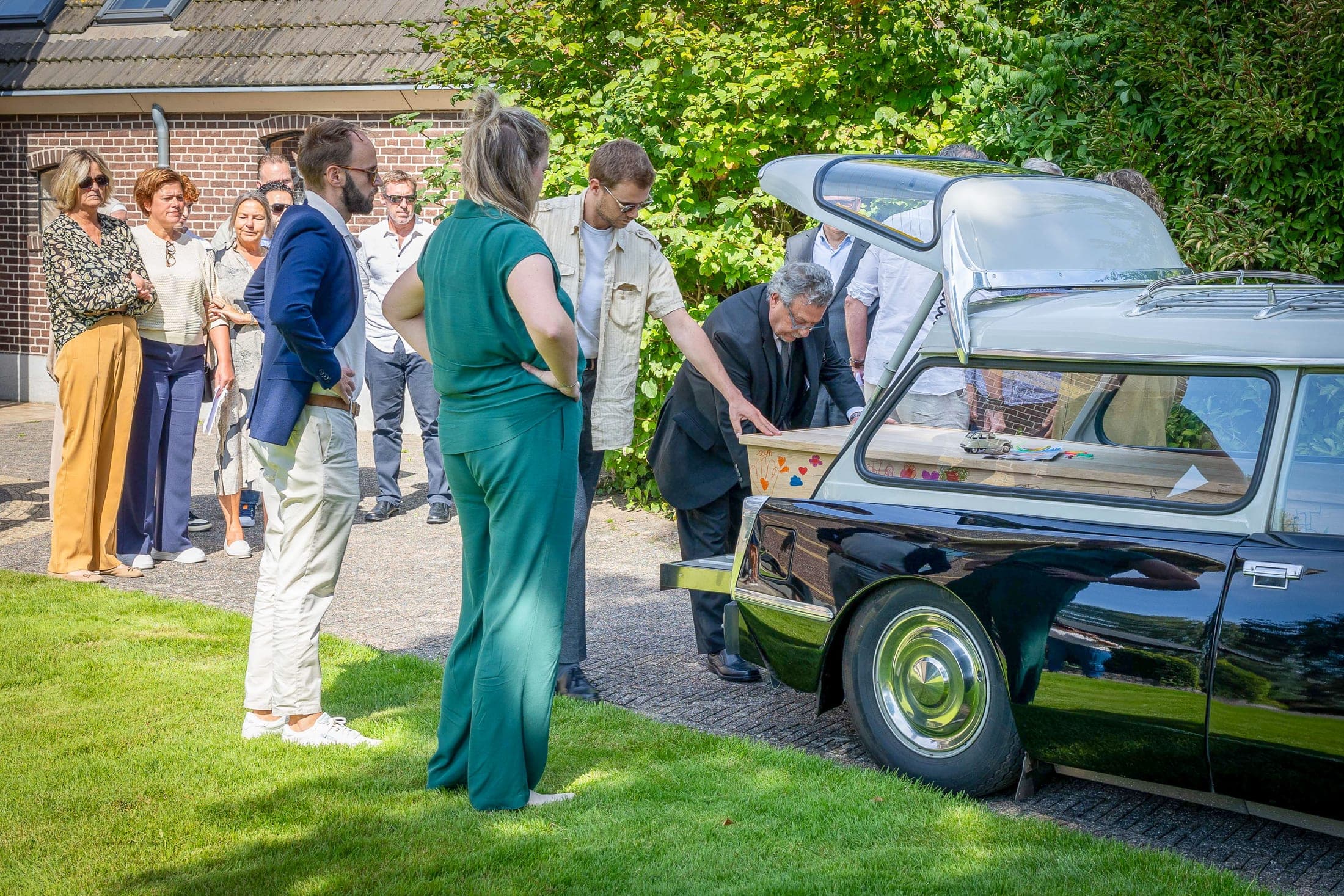 Nabestaanden bij de rouwauto na de ceremonie