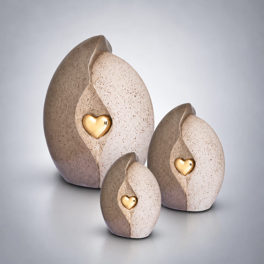 Drie urnen van natuursteen met een gouden hart